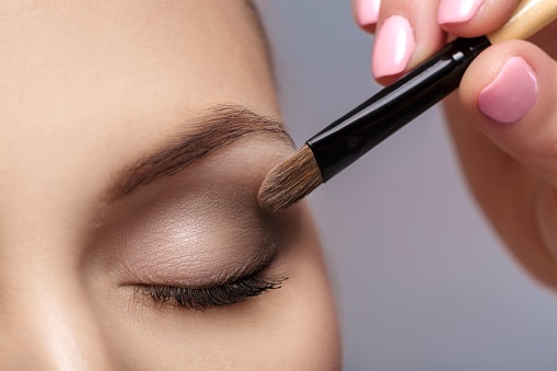 makeup artist apply makeup brush for eyes. makeup for a young beautiful girl. brown eye shadow. close up